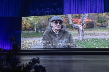 na ekranie wyświetla się video - kobieta siedzi na ławce w parku. podpis Prof. Maria Poprzęcka, Wydział Artes Liberales UW